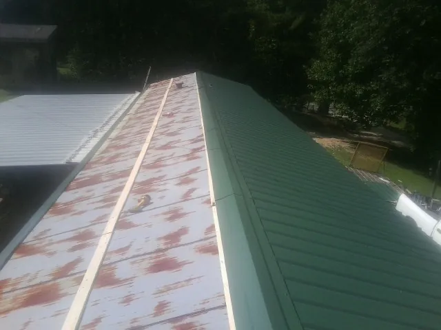 Old rusted panels beside newly installed green metal roofing — Wind Damage Roof Repair by Roofing Brothers in Emmett