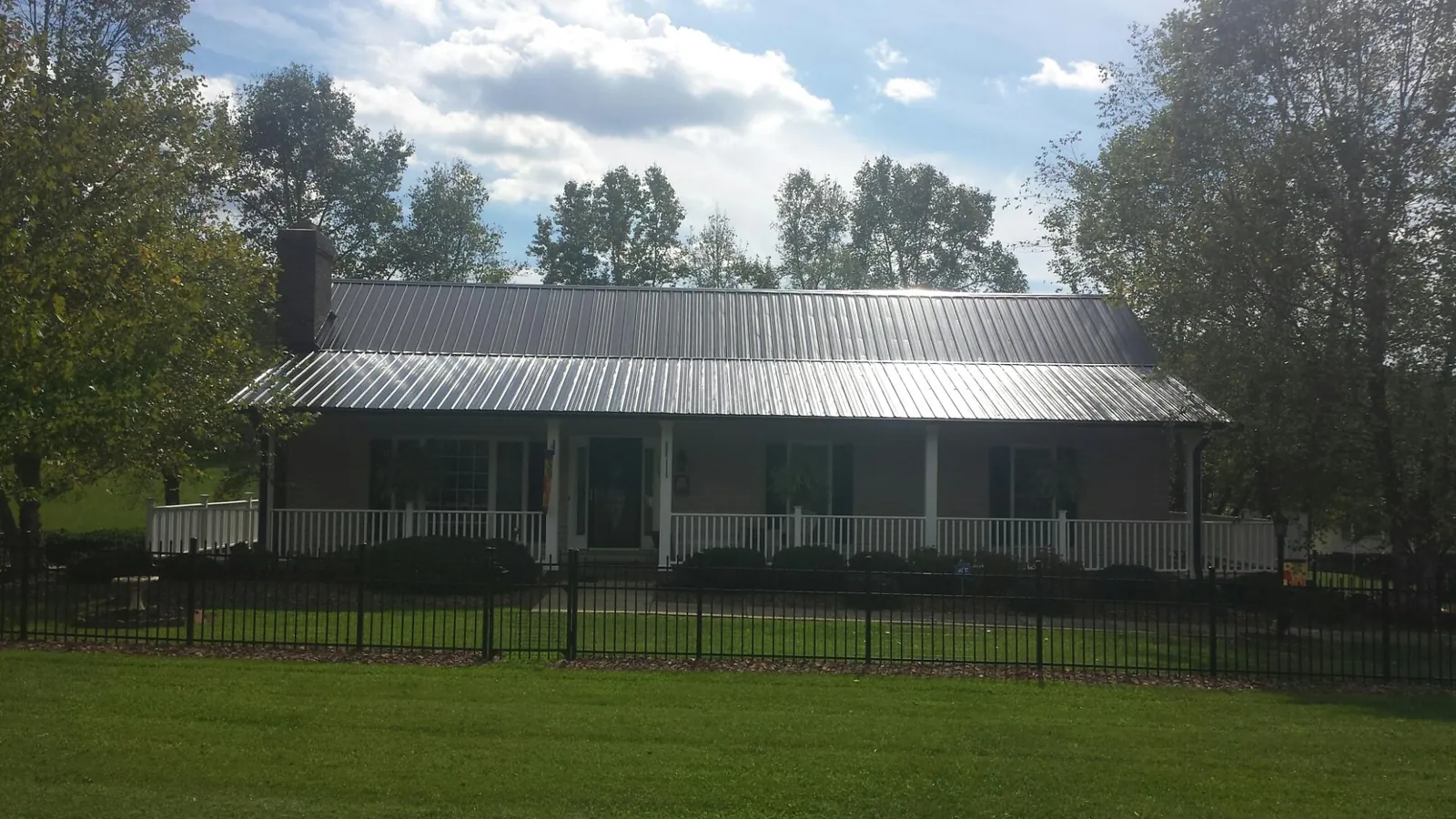 Gray metal roof on a brick ranch with a full width front porch — Gutter Guard Installation work by our crew in Emmett