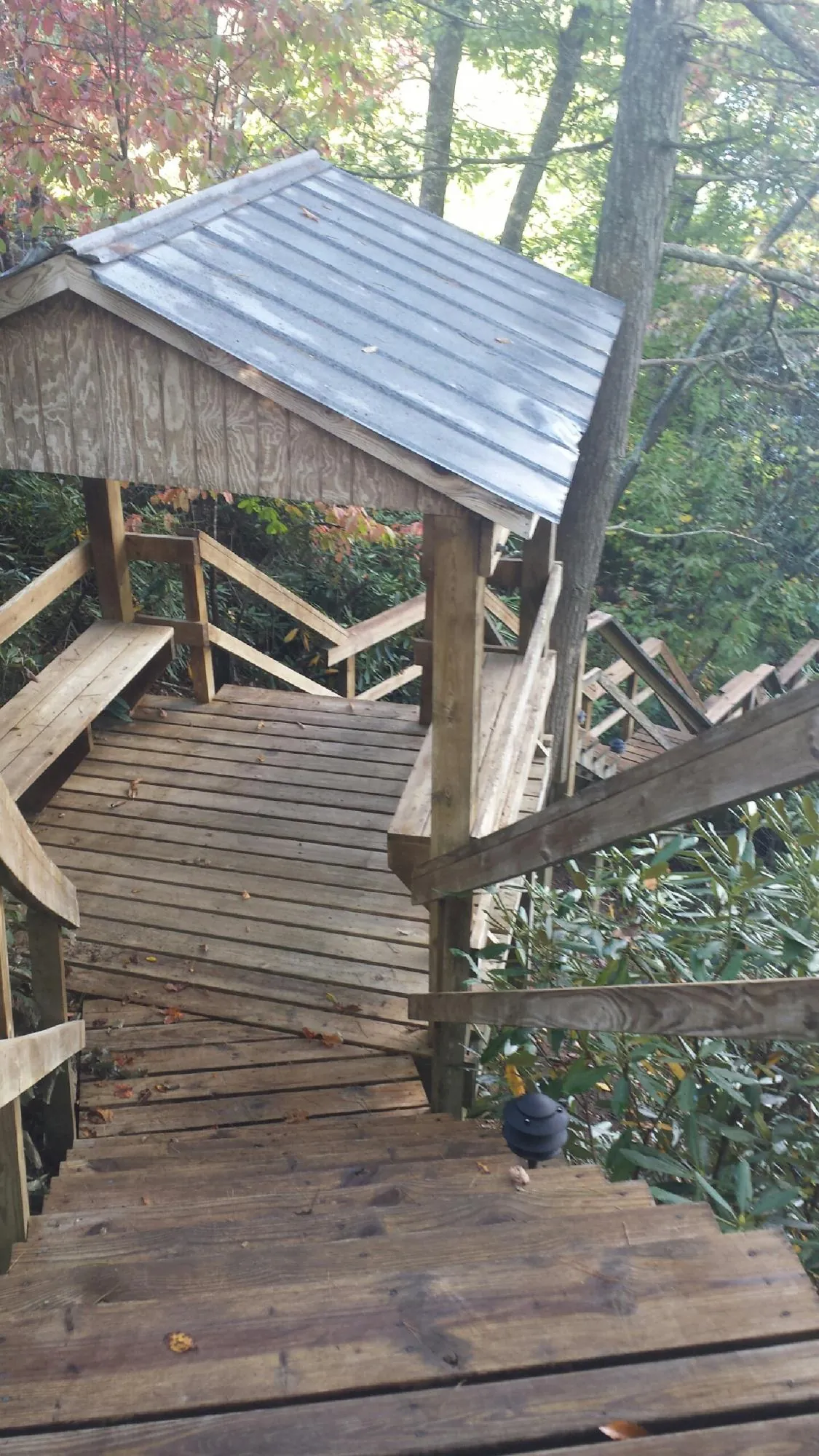 Metal roofed shelter over wooden steps on a wooded walkway — Skylight Repair & Installation work by our crew in Emmett