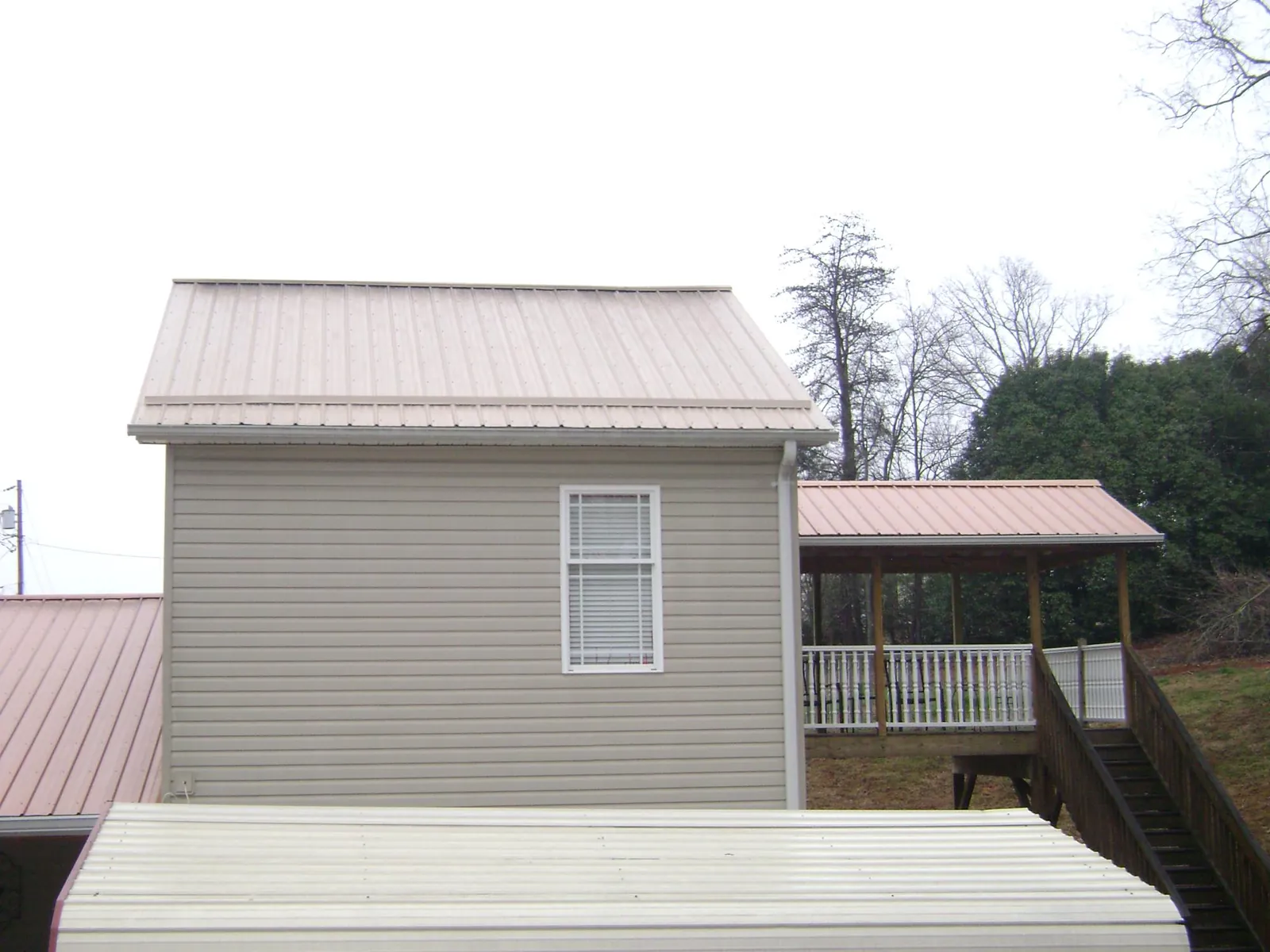 Tan metal roofs on a two story addition and attached porch, from a Roof Replacement job in Emmett